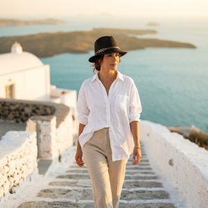 استایل و تن‌خور کلاه فدورا حصیری زنانه آی ام بر سر مدل در حال قدم زدن در مسیر ساحلی تابستانی