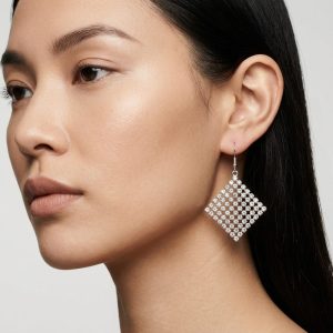 نمای گوشواره آویز مجلسی آی ام طرح لوزی مشبک نقره ای روی گوش مدل زنانه در آتلیه