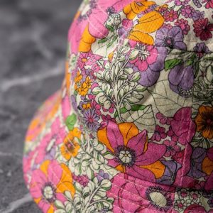 نمای نزدیک از جزئیات بافت پارچه پنبه‌ای و دوخت کلاه باکت گلدار زنانه آی ام