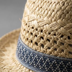 نمای نزدیک از بافت الیاف طبیعی و نوار هندسی کلاه حصیری زنانه
