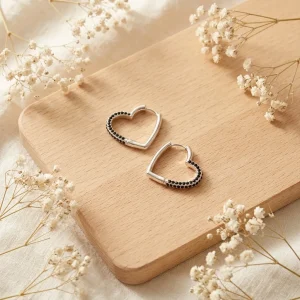 چیدمان دکوراتیو گوشواره حلقه‌ای قلبی نقره‌ای آی ام روی تخته چوبی