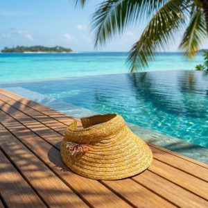 کلاه آفتابگیر حصیری زنانه در فضای استخر و عرشه چوبی ساحلی